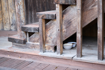A shot of food bowls for cats under wooden stairs
