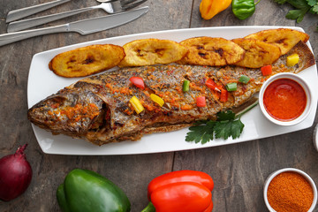 Grilled fish curry with plantain and salad. African national dish. Nigerian fish curry. Healthy lifestyle meal. Vegetarian food