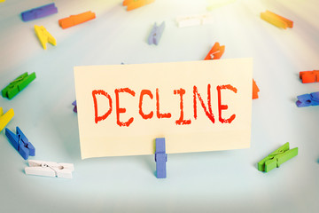 Conceptual hand writing showing Decline. Concept meaning Become smaller fewer less Decrease Politely refuse reject say no Colored clothespin paper empty reminder blue floor officepin