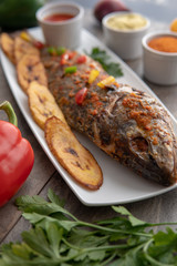 Grilled fish curry with plantain and salad. African national dish. Nigerian fish curry. Healthy lifestyle meal. Vegetarian food