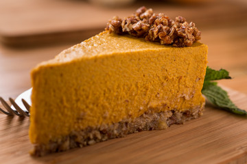 Pumpkin Pie with raw granola crust on wood with fork