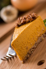 Pumpkin Pie with raw granola crust on wood with fork
