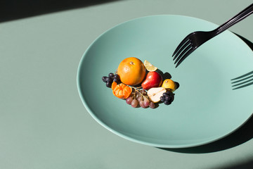 black fork reaching tiny fruit on a mint green color plate
