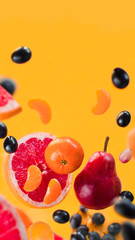 fruit levitation, grapefruit, grapes, tangerine, pear flying on yellow background