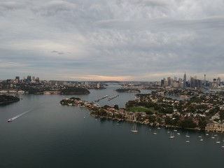 Obraz premium Panoramic drone aerial view over Sydney harbour on a cloudy sunset showing the nice colours of the harbour foreshore