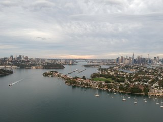 Panoramic drone aerial view over Sydney harbour on a cloudy sunset showing the nice colours of the harbour foreshore