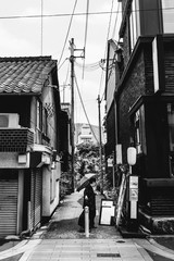 Woman with umbrella walking at small alley in Kyoto downtown, Japan (in black and white)