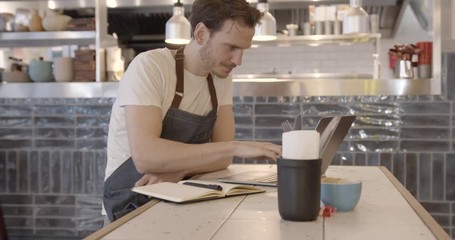 Restaurant chef working on laptop in commercial kitchen, small business, technology, entrepreneur, finance