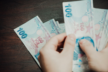 Many hundred Turkish lira on wooden table background texture. bundles of money scattered on the office desk. wealth and income concept. Counting money. 