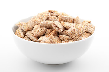 Vitamin and fibre rich meal and everyday breakfast concept with generic shredded wheat cereal in bowl isolated on white background with clipping path cutout