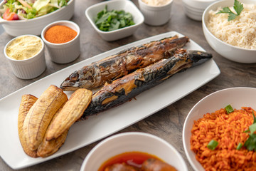 African national food dish grilled meat and chicken dish wings home-made Cuisine with plantain with jollof rice. Nigerian Jolofrice. Grilled African fish dish and meal with chilli banana and plantain.