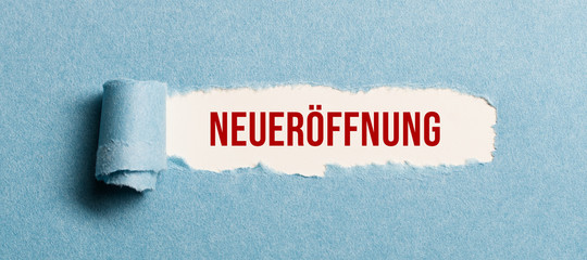 torn paper revealing the German word for REOPENING on white background
