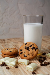 cookies with chocolate and milk on a light wooden table