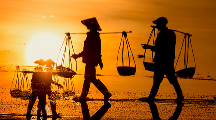 Salt and Silhoutte of salt farmer on salt field Hon Khoi, Nha Trang, Khanh Hoa, Vietnam.