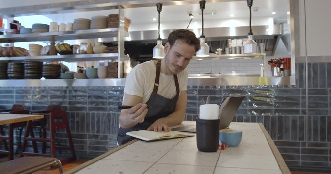 Restaurant chef working on laptop in commercial kitchen, small business, technology, entrepreneur, finance