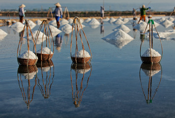 Salt and Silhoutte of salt farmer on salt field Hon Khoi, Nha Trang, Khanh Hoa, Vietnam.
