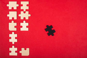 wooden puzzles of white and black color on a red background top view. stand out, leader 