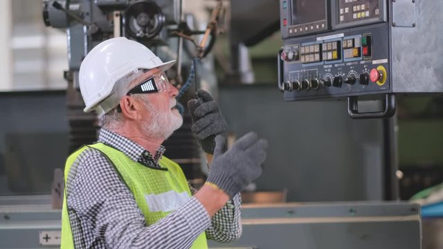 Old technician or engineer angry with the machine and use walki talky to contact support team for helping in factory.