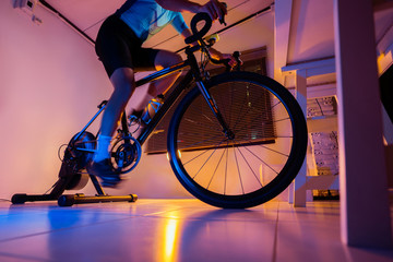 Asian man cycling on the machine trainer he is exercising in the home at night.he play online bike game