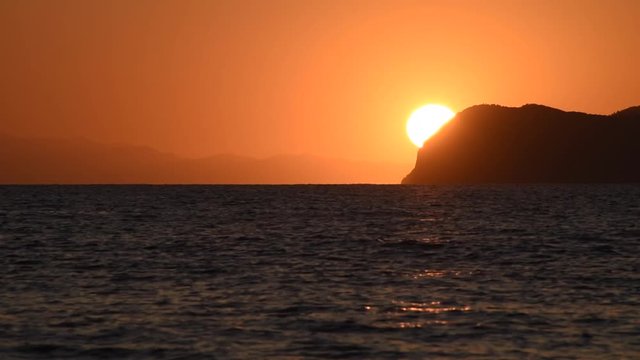 Sea landscape with the sun behind the mountain at sunset in the Elba Island.