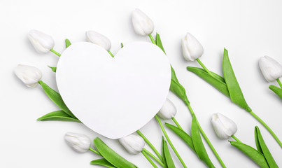 Romantic love layout made with paper card shape of heart and tulips on white pastel background. Template of festive congratulations. Wedding greeting concept.