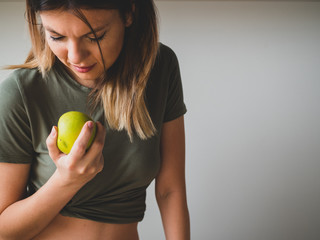 Beautiful sporty woman want to bite a green apple in hand. Healthy food