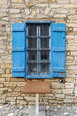 Fototapeta na wymiar Old window with metal bars and blue open shutters in Limassol. Cyprus