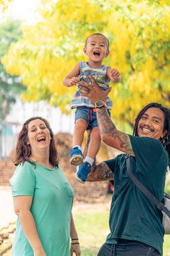 Mixed race family playing under a yellow Handroanthus chrysanthus tree in full bloom