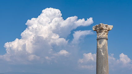 Antique column against the blue skies with a cloud in the ancient city of Kourion (Cyprus)