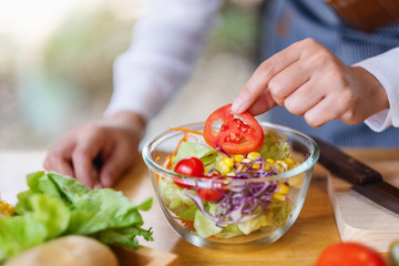Closeup image of a female chef cooking a fresh mixed vegetables salad in kitchen