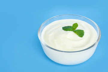 Close up yogurt  in glass bowl  with wooden spoon on blue background