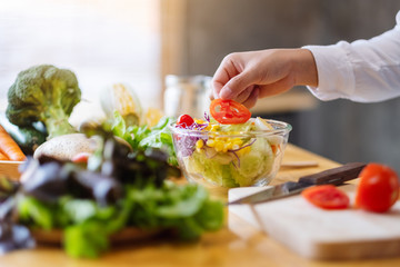Closeup image of a female chef cooking a fresh mixed vegetables salad in kitchen