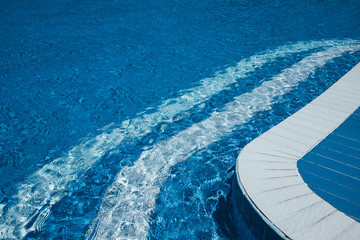 Steps to the pool, blue clear water in swimming pool, safe descent to the pool, close-up steps through the water