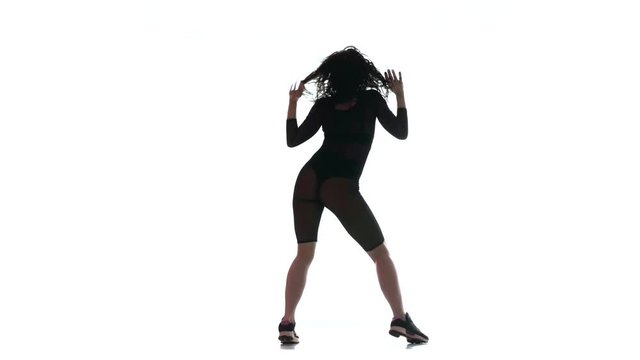 young beautiful woman in a black transparent tight suit energetically dancing dancehall, street dance, twerk against white background,  isolated 