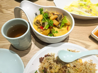 The traditional Cantonese cuisine. There are curry beef, poached vegetable, egg fried rice, a cup of black tea and a dish of plum sauce on the table. 