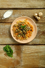 Plate of pasta with mushrooms in a creamy sauce with spinach on a wooden table.