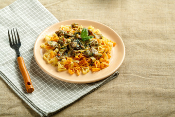 pasta with mushrooms in a creamy sauce with spinach on a linen tablecloth on a napkin with a fork.