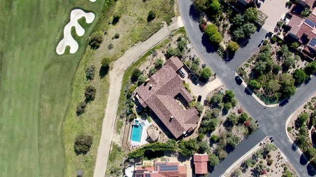 Aerial view of big luxury villa with pool located next the golf course and green valley in a private community, San Diego, California.