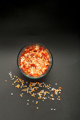 Glass jar with yellow lentils on a black background.