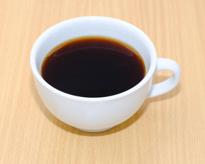 Coffee cup on wooden kitchen table. Top view with morning sunlight