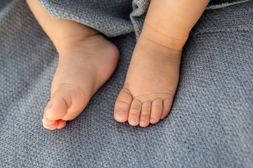 Baby girl feet on gray background at sunset outdoor, natural light