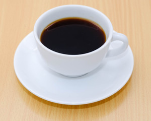 Coffee cup on wooden kitchen table. Top view with morning sunlight