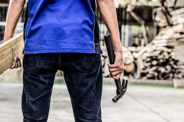 A carpenter holding his back with a hammer and a piece of wood standing back with a space for text.