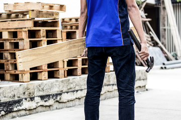 The carpenter clutched his back with a hammer and a piece of wood.