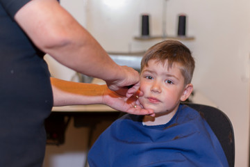 Boy is having a haircut at home by grandmother