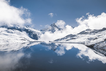 Fototapeta na wymiar Jungfrau region. Top of Europe. Place for tourist attraction to to visit in Switzerland, hiking in snow mountains. Swiss alps is reflecting in blue Bachalpsee lake. Destination for traveler and hiker