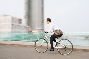 Blurred image of Asian man mad riding bicycle in urban city commuting with speed and hipster trendy...