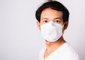 Closeup Asian handsome Man wearing surgical hygienic protective cloth face mask against coronavirus, studio shot isolated white background, COVID-19 medical concept