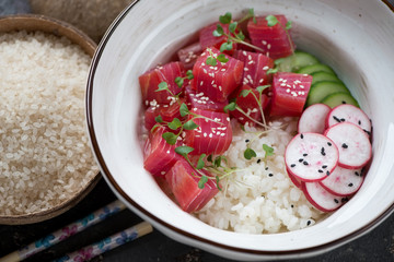 Close-up of a poke bowl with tuna fillet, white rice, radish, cucumber and sesame, selective focus