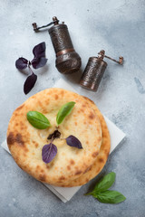 Ossetian pies on a light-blue stone background with pepper grinders, view from above, vertical shot